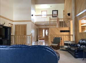 Living room featuring a towering ceiling, tile patterned floors, and wood walls