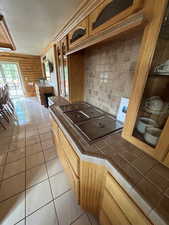 Kitchen with backsplash, tile countertops, wood walls, and light tile patterned flooring