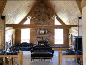 Living room featuring a fireplace, carpet floors, high vaulted ceiling, and rustic walls