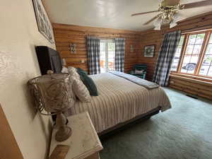 Carpeted bedroom with log walls, a textured ceiling, and ceiling fan