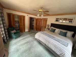 Carpeted bedroom featuring ceiling fan, a closet, and a textured ceiling