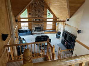 Living room with carpet, high vaulted ceiling, a fireplace, log walls, and wood ceiling