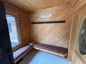 Interior space with log walls, tile patterned floors, and wood ceiling