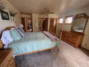 Carpeted bedroom with ceiling fan, a textured ceiling, and a closet