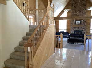 Stairway featuring log walls, tile patterned flooring, a fireplace, and ceiling fan