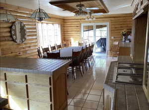 Dining space featuring rustic walls, ceiling fan, and light tile patterned floors