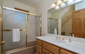 Bathroom featuring vanity and bath / shower combo with glass door