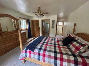 Carpeted bedroom with ceiling fan, a textured ceiling, connected bathroom, and a closet