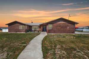 View of front of property with a yard, brick siding, fence, and metal roof