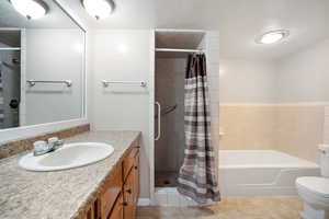 Full bathroom with independent shower and bath, vanity, tile patterned floors, and toilet