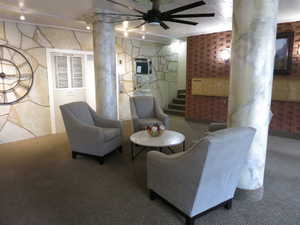 Living room featuring carpet flooring, decorative columns, and ceiling fan