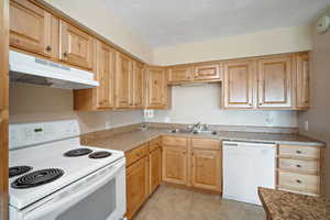 Kitchen featuring sink, light brown cabinets, white appliances, and light tile patterned floors