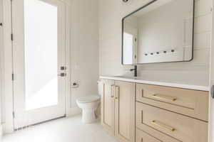 Bathroom with tile patterned flooring, vanity, toilet, and wooden walls