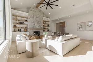 Living room with built in shelves, beam ceiling, a stone fireplace, and light wood-type flooring