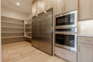 Kitchen with built in appliances, decorative backsplash, light brown cabinetry, and light hardwood / wood-style floors