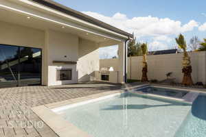 View of pool featuring a patio, an outdoor kitchen, and an outdoor brick fireplace