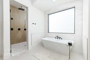 Bathroom featuring vaulted ceiling, tile patterned flooring, tile walls, and shower with separate bathtub