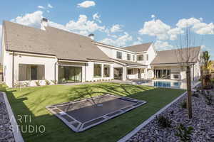 Back of property with a swimming pool with hot tub, a patio, and a trampoline