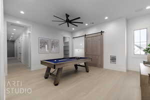 Rec room with a barn door, ceiling fan, light hardwood / wood-style flooring, and pool table