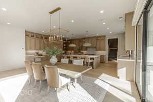 Dining area featuring sink, an inviting chandelier, and light wood-type flooring