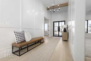 Corridor with french doors, light wood-type flooring, an inviting chandelier, and beam ceiling