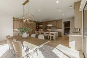 Dining space featuring sink, a notable chandelier, and light wood-type flooring