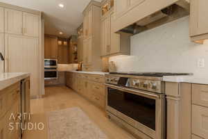 Kitchen with premium range hood, light brown cabinets, stainless steel appliances, and light wood-type flooring