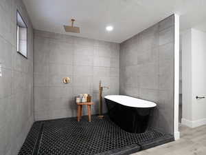 Bathroom featuring a textured ceiling, tile walls, and plus walk in shower