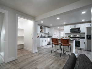 Kitchen featuring white cabinetry, sink, a breakfast bar, a kitchen island, and appliances with stainless steel finishes