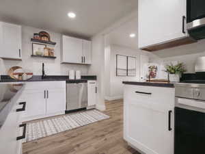 Kitchen featuring light wood-type flooring, white cabinets, sink, dishwasher, and white stove