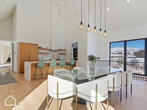 Dining area with a mountain view, light wood-type flooring, sink, and high vaulted ceiling