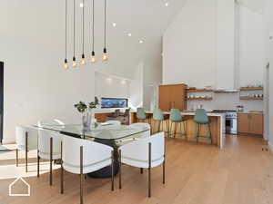 Dining area with light wood-type flooring and high vaulted ceiling