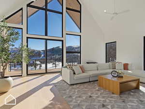 Living room with ceiling fan, a towering ceiling, and a mountain view