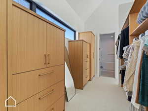 Walk in closet featuring light carpet and vaulted ceiling