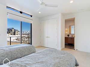 Carpeted bedroom featuring ceiling fan, ensuite bath, and a closet