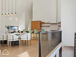 Interior space featuring light wood-type flooring, pendant lighting, and a towering ceiling