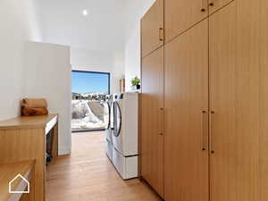 Clothes washing area with washing machine and dryer and light wood-type flooring