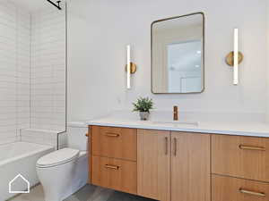 Full bathroom featuring tiled shower / bath, vanity, and toilet