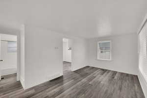 Spare room featuring dark hardwood / wood-style floors, crown molding, and a healthy amount of sunlight