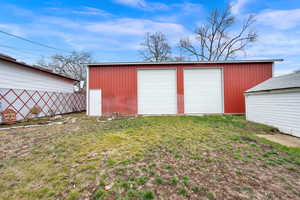 View of outdoor structure featuring a garage and a lawn