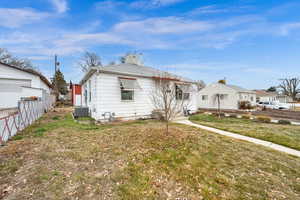 Rear view of property featuring a yard and central AC