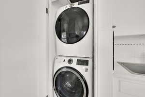 Clothes washing area featuring stacked washer and dryer