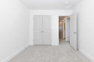 Unfurnished bedroom with light carpet and a closet