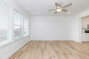 Unfurnished living room with light wood-type flooring and ceiling fan