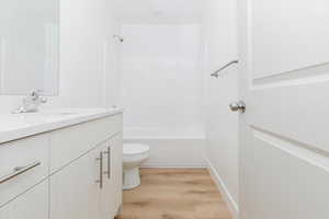 Full bathroom with shower / bathing tub combination, wood-type flooring, vanity, and toilet