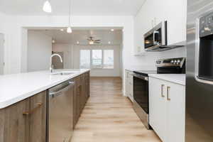 Kitchen featuring appliances with stainless steel finishes, ceiling fan, sink, decorative light fixtures, and white cabinetry