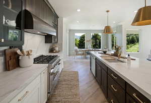 Kitchen with appliances with stainless steel finishes, backsplash, hanging light fixtures, and sink