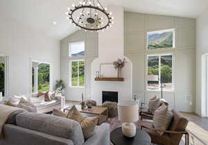 Living room featuring a fireplace, wood-type flooring, a chandelier, and high vaulted ceiling