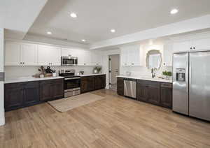 Kitchen with dark brown cabinetry, sink, stainless steel appliances, and light wood-type flooring