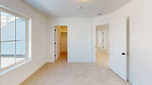 Unfurnished room featuring light carpet, baseboards, visible vents, and a healthy amount of sunlight